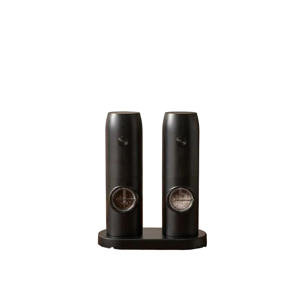 Two black ceramic grinders on a wooden surface withDOMISANA branding.