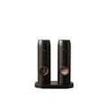 Two black ceramic grinders on a wooden surface withDOMISANA branding.