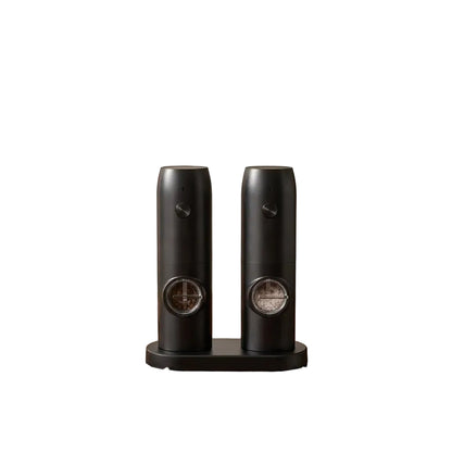 Two black ceramic grinders on a wooden surface withDOMISANA branding.